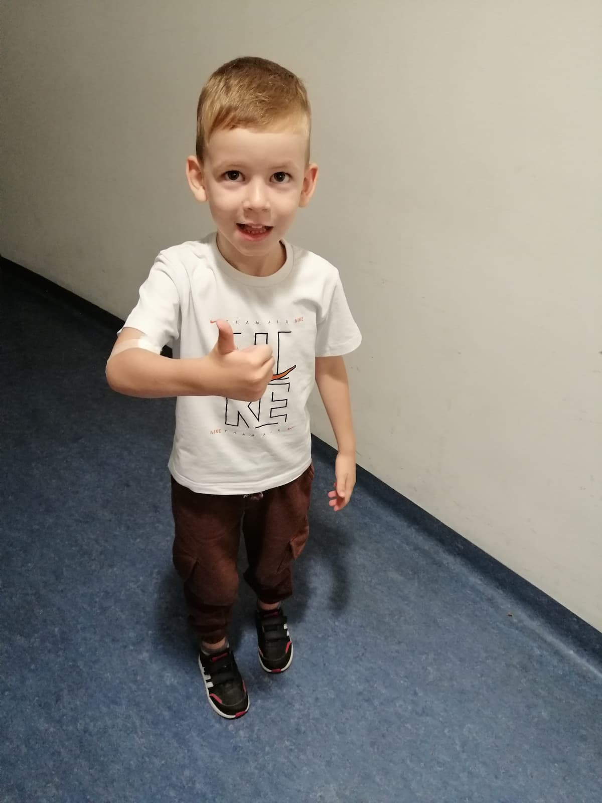 Dijete s palcem gore u hodniku